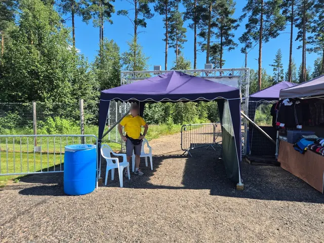 Entrén till festivalområdet med lila partytält och funktionär i gul tröja.