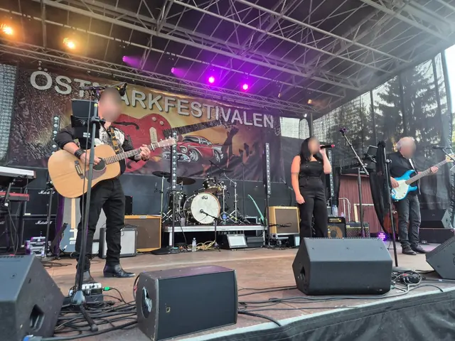 Band spelar på Östmarksfestivalens stora scen med akustisk gitarr, sång och bas under lila scenljus.